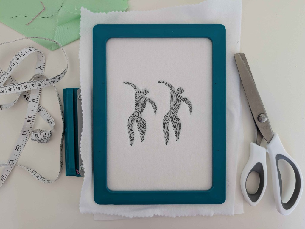 Two embroidered figures in a teal hoop. The left figure is Wave Fill, with lines flowing along the pose. The right figure is Contour, with lines following the outline.